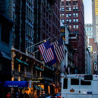 ニューヨークの高層ビルが立ち並ぶ街並みとアメリカ国旗の写真
