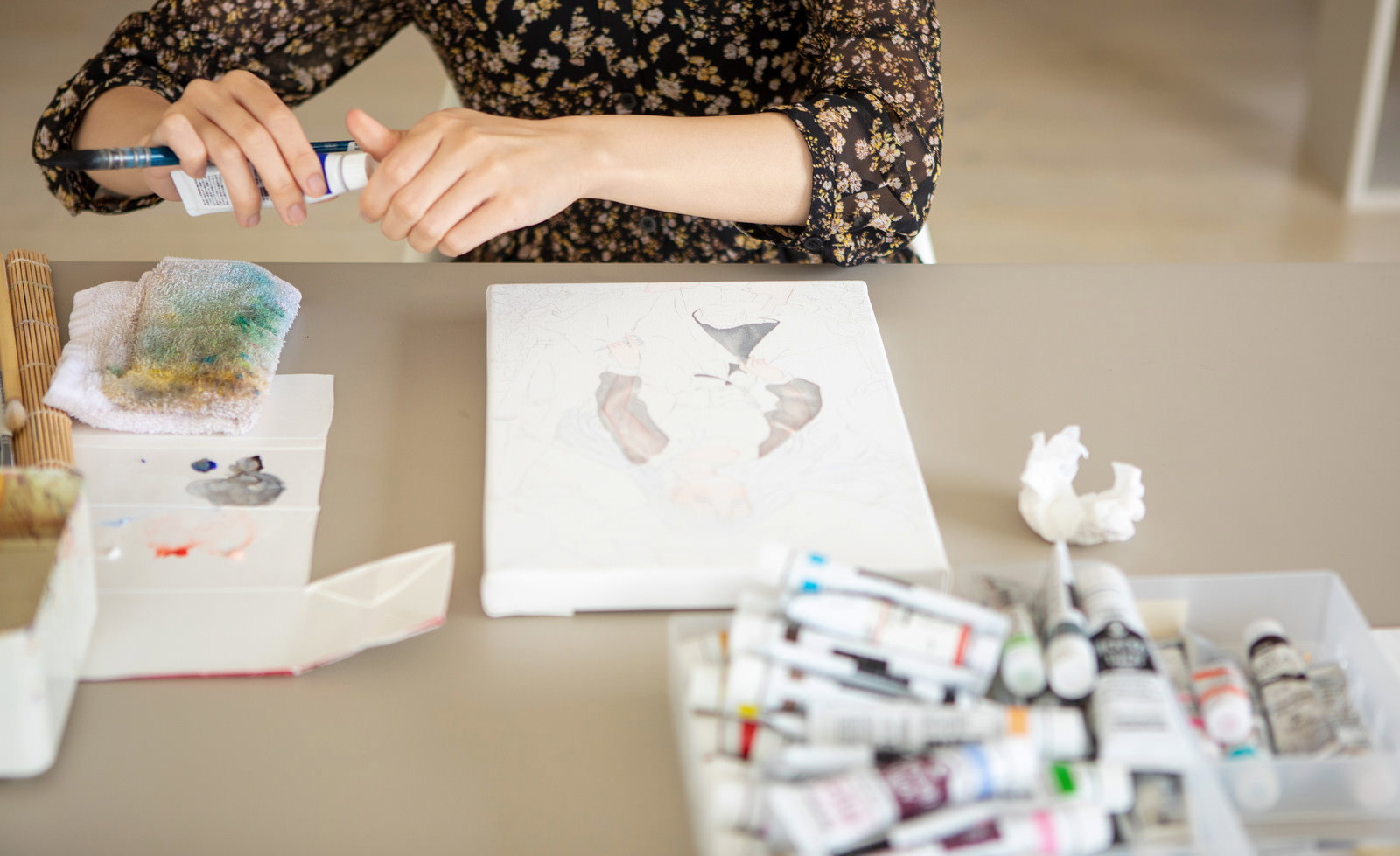 白いキャンバスの前で絵の具パレットを手に持つ女性