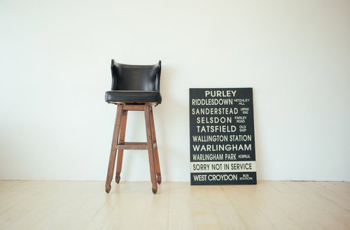 無造作に置かれた黒いレザーのバーチェアと看板