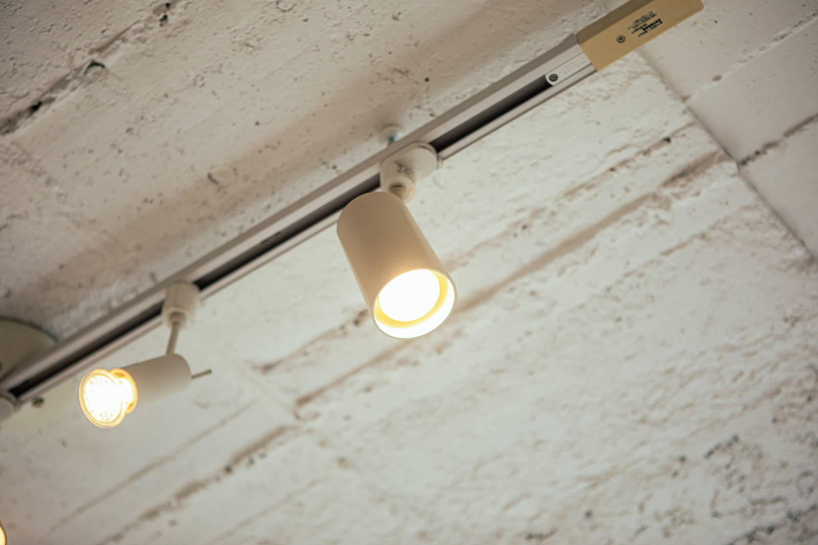 Warm light shining from rail-mounted lighting fixtures installed on a white ceiling