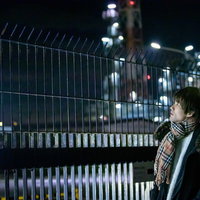 工場夜景を背景にマフラーを巻いた男性が待ち合わせで立つの写真