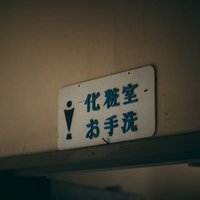 「化粧室」「お手洗い」と書かれた廃墟の男子トイレの写真
