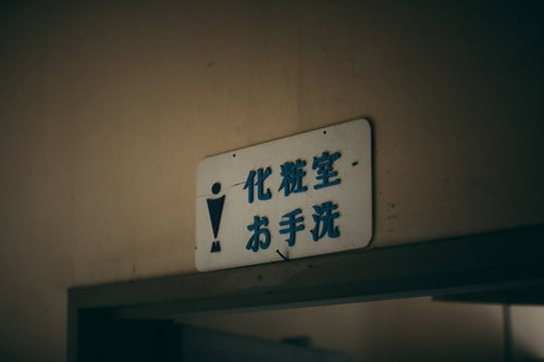 「化粧室」「お手洗い」と書かれた廃墟の男子トイレ