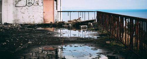海が見える倒壊した廃墟と足元の水たまり