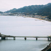工場越しに見る漁村の海岸風景、工業と漁業が共存する沿岸地域の写真