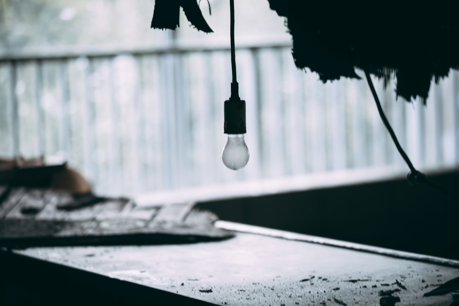 廃墟の薄暗い室内で天井からぶら下がる一つの電球
