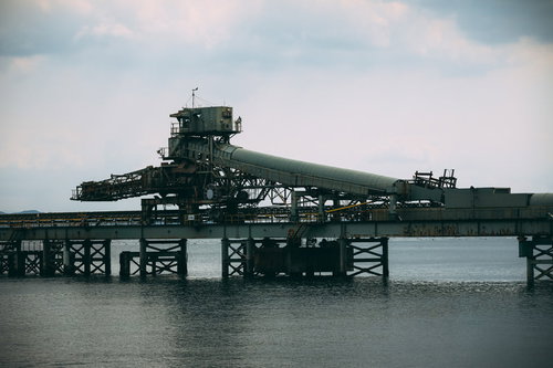 曇り空の下、海の上に建つ工業施設と港湾風景