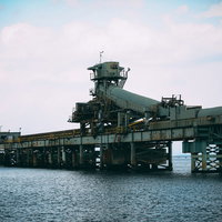 海上に浮かぶ仄暗い廃工場と桟橋の写真