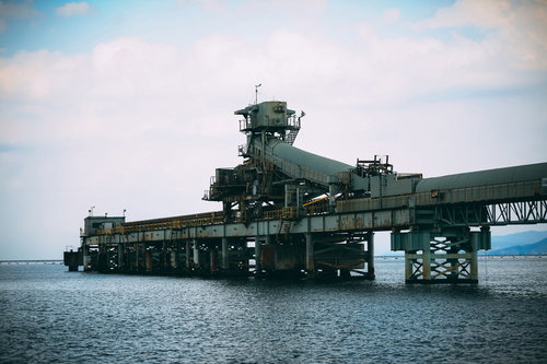 海上に浮かぶ仄暗い廃工場と桟橋