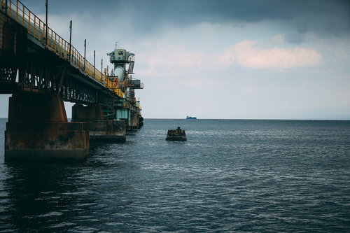 海上工場の先に見える運搬船と工業地帯の港湾風景