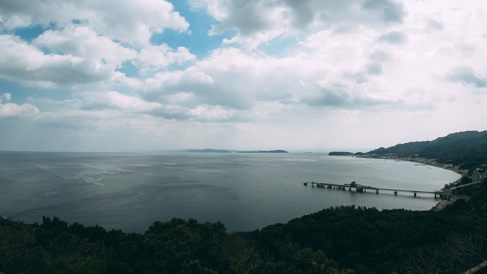 高台から見下ろす海岸沿いの工場群と漁村の風景