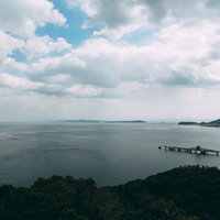 見晴らしのいい山から見下ろす海と工場と漁村の沿岸風景の写真