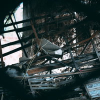 割れた板や瓦礫が散らばる廃墟の内部と崩壊した建物構造の写真