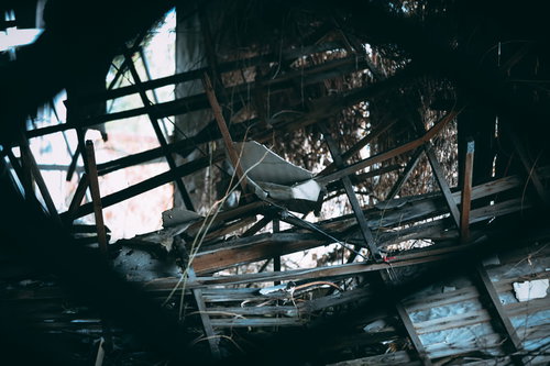 割れた板や瓦礫が散らばる廃墟の内部と崩壊した建物構造