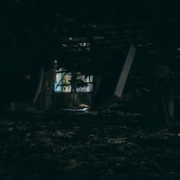 暗がりから見る天井が大きく崩れ落ちる廃墟の写真