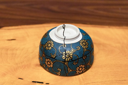 金継ぎで修復された紺色の花柄お椀、木製テーブルに置かれた和食器