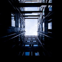 高層ビルに囲まれた四角い空を見上げた都市風景の写真