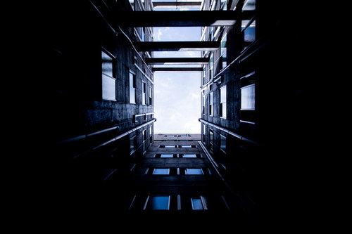 高層ビルに囲まれた四角い空を見上げた都市風景