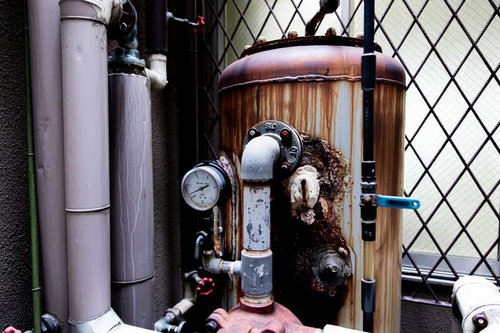 錆び付いたタンクと複数の配管が組み合わされた老朽化した設備