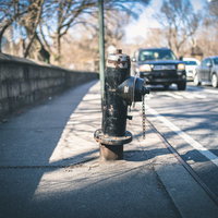 歩道に設置された錆び付く消火栓と駐車場の街並みの写真
