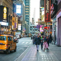 ニューヨークの横断歩道を行き交う観光客と電飾看板の写真