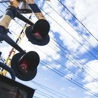 踏切と電線が張り巡らされた線路と青空の写真