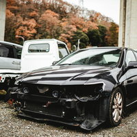廃車施設に並ぶ事故車と秋の紅葉の写真