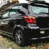 廃車工場に置かれたナンバープレートの外された黒い自動車の写真