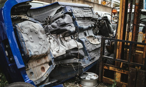工場内で横転したままの廃車と破損したボディの大破車両
