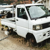 前輪のタイヤが外れた白い軽トラックの事故車の写真
