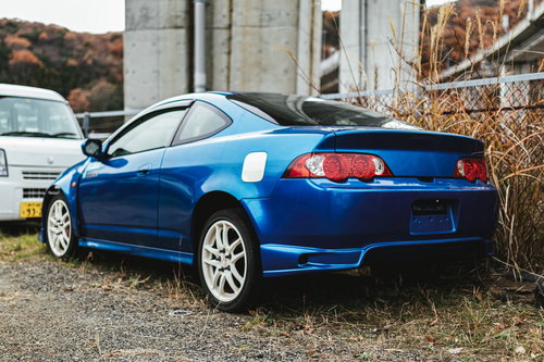 ナンバープレートを外された青いクーペ。駐車場に停められた廃車