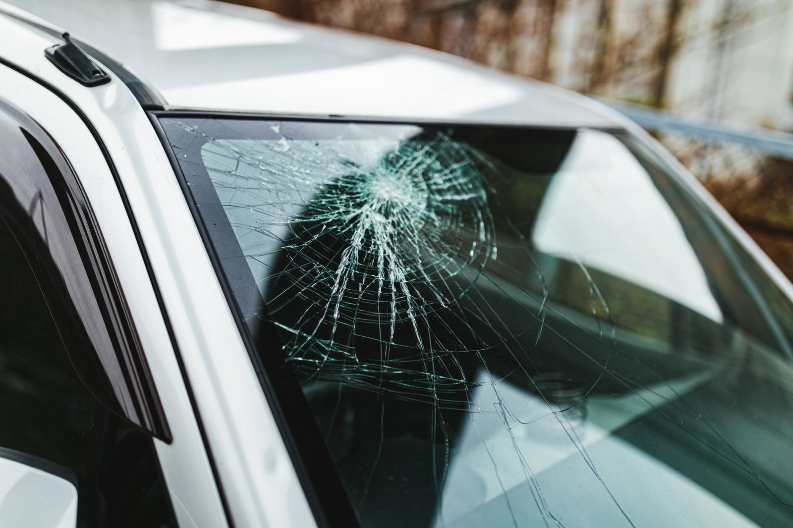 車のフロントガラスにクモの巣状のヒビが放射状に広がっている