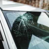 車のフロントガラスがクモの巣状にヒビが入った自動車事故の写真