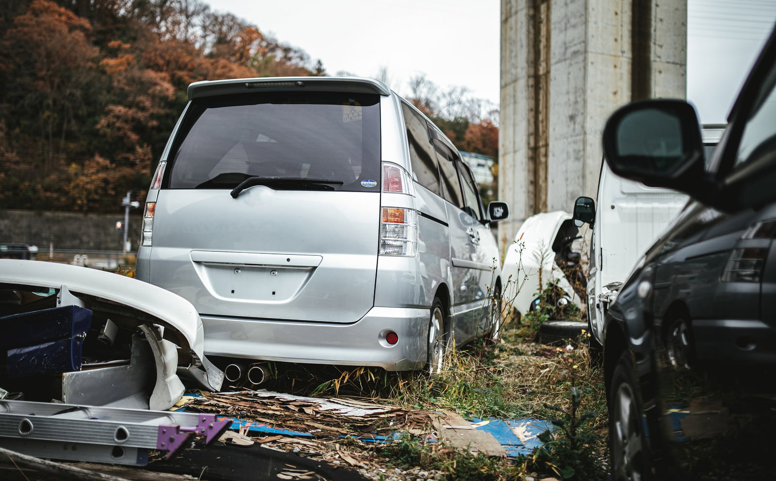 廃車工場の敷地内に複数の自動車が並んで停められている様子
