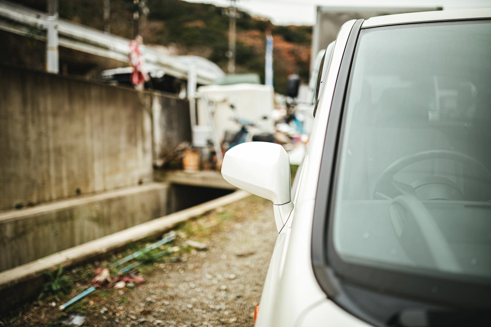 事故で破損した車の右側サイドミラー、背景に住宅街