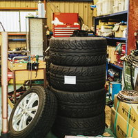 自動車整備工場に積み重ねられたスペアタイヤと工具の写真