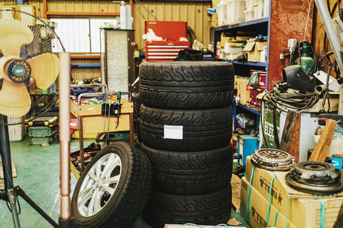 自動車整備工場に積み重ねられたスペアタイヤと工具