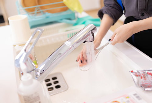 キッチンのシンクで調理器具を丁寧に洗う手元