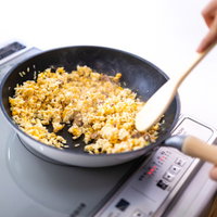 IHコンロでチャーハンを炒める手元の調理風景の写真
