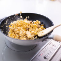 黒いフライパンでチャーハンを炒める手元の調理風景の写真