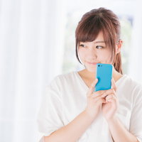 フリマアプリで欲しい商品を落札できた青いスマホを持つ女性の写真