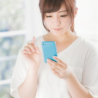 スマホのアプリで簡単申請する女性のスマートフォン操作の写真