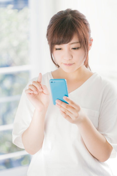 スマホのアプリで簡単申請する女性のスマートフォン操作