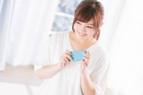 スマホに吉報が届いて思わずニッコリ笑顔の女性