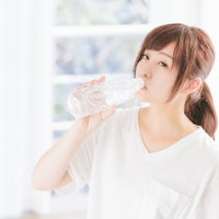 起床直後の水分補給で水を飲む女性の写真