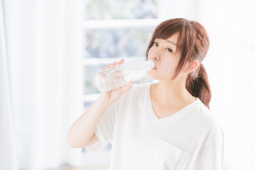 起床直後の水分補給で水を飲む女性