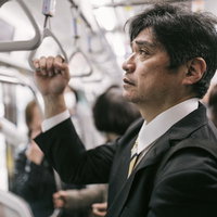 夜遅くまで勤めて終電で帰る会社役員・満員電車での帰宅の写真