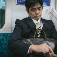 通勤中に電車内でニュースアプリを確認するサラリーマンの写真