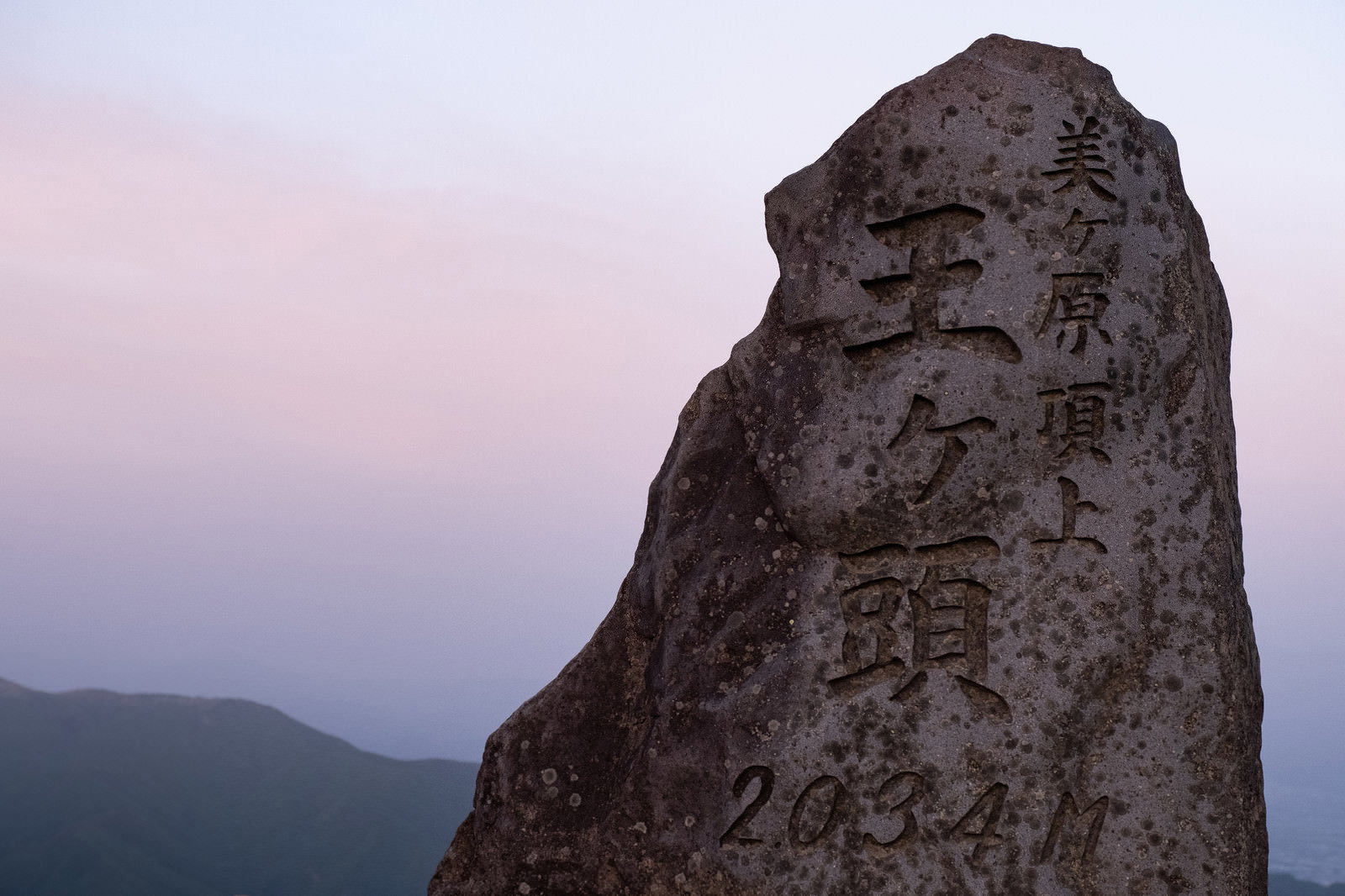 美ヶ原高原の王ヶ頭山頂に立つ石碑と夕暮れの山並み
