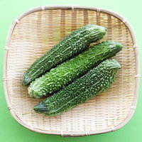 竹ざるに並んだゴーヤ3本（夏野菜）の写真